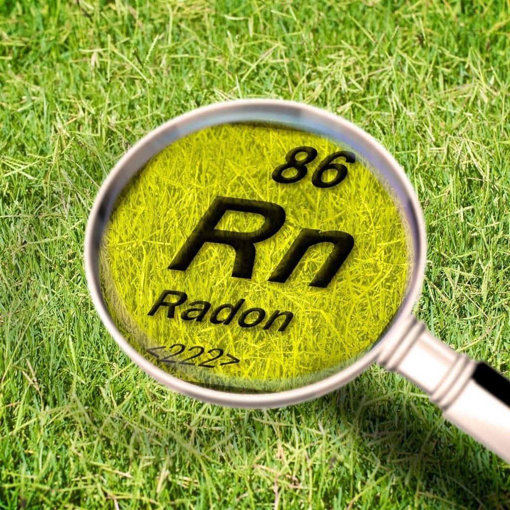 Magnifying glass over grass revealing the periodic table symbol for radon (Rn), element 86